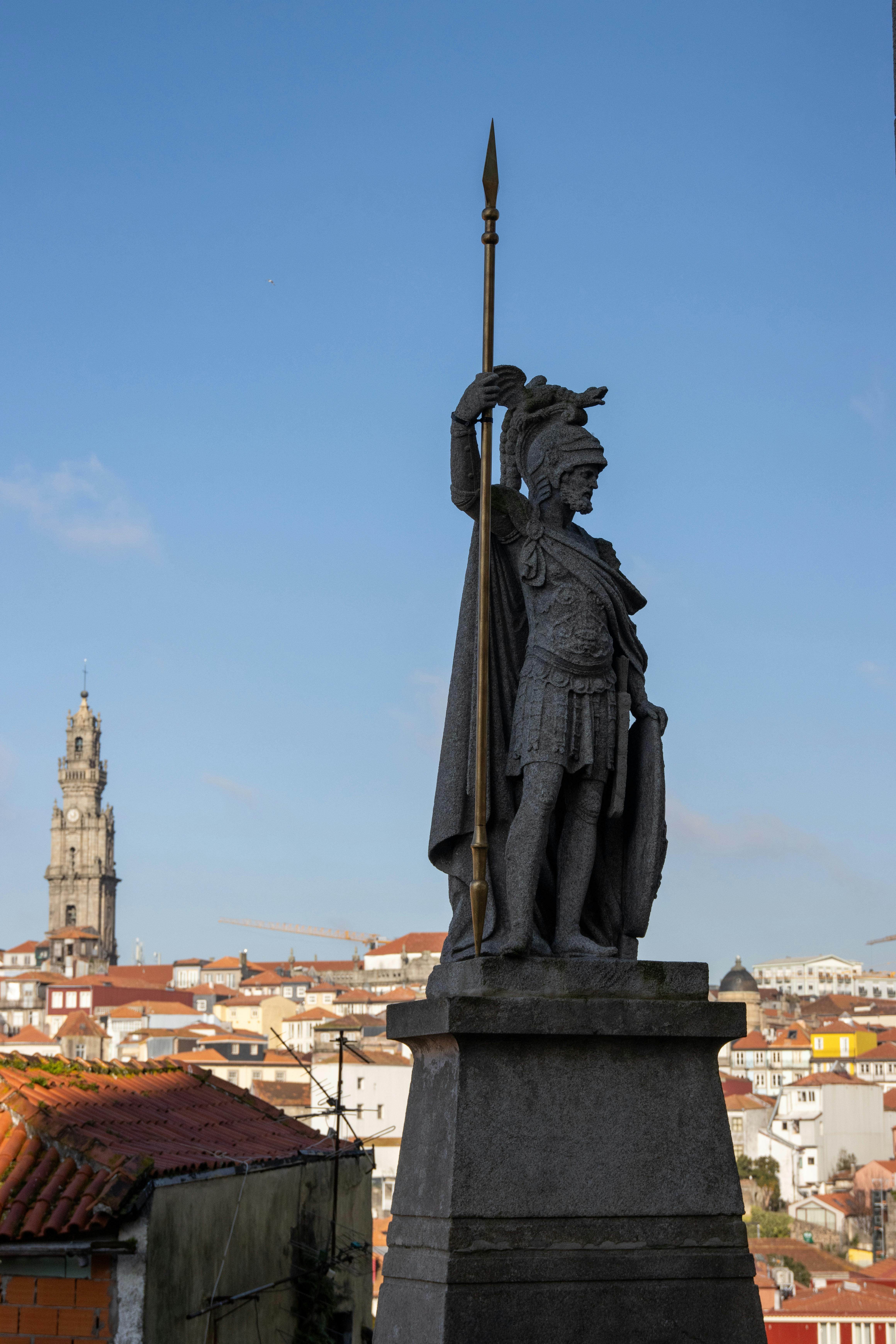 Statue of Roman soldier with spear in Porto, Portugal, showcasing historical architecture.
