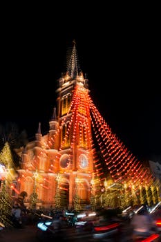 Illuminated cathedral with festive lights at night, creating a vibrant holiday atmosphere.