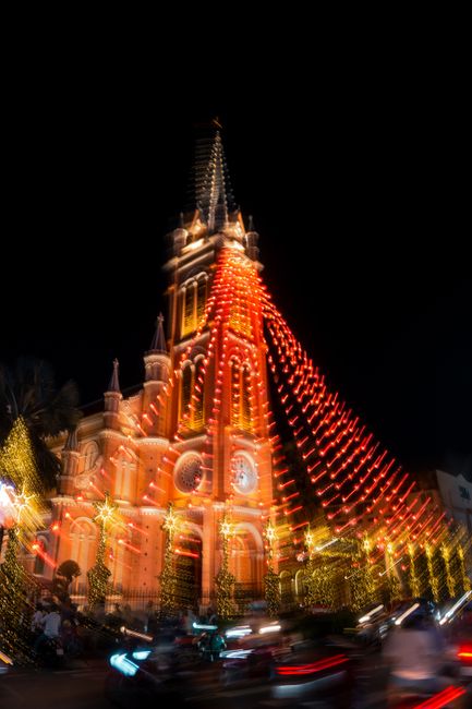 Illuminated cathedral with festive lights at night, creating a vibrant holiday atmosphere.