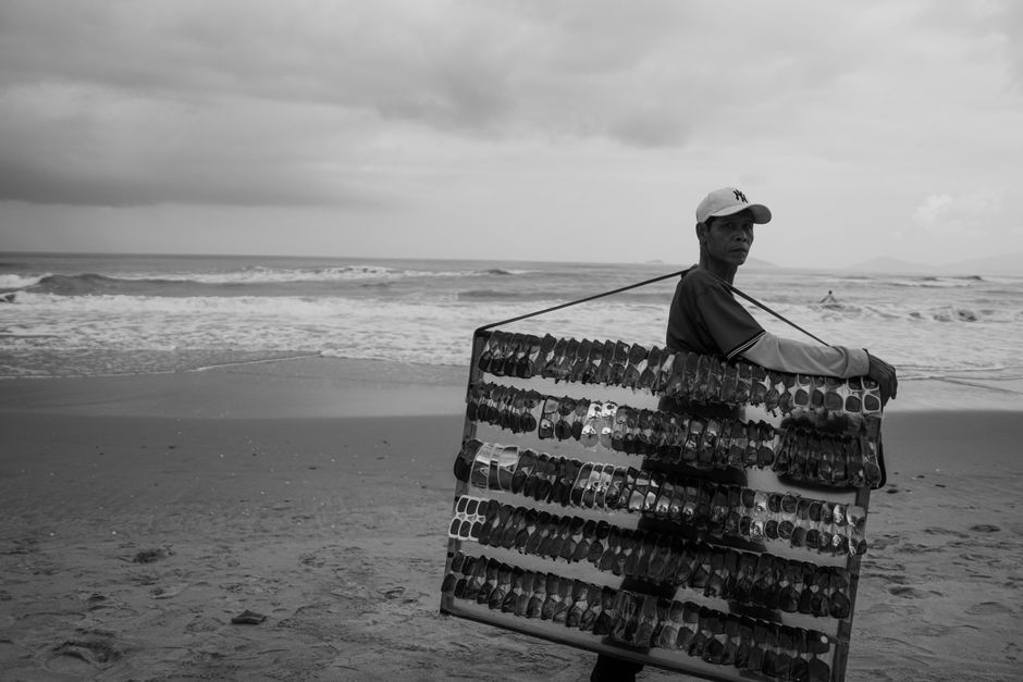 Portrait of a beach vendor carrying sunglasses display by the sea.