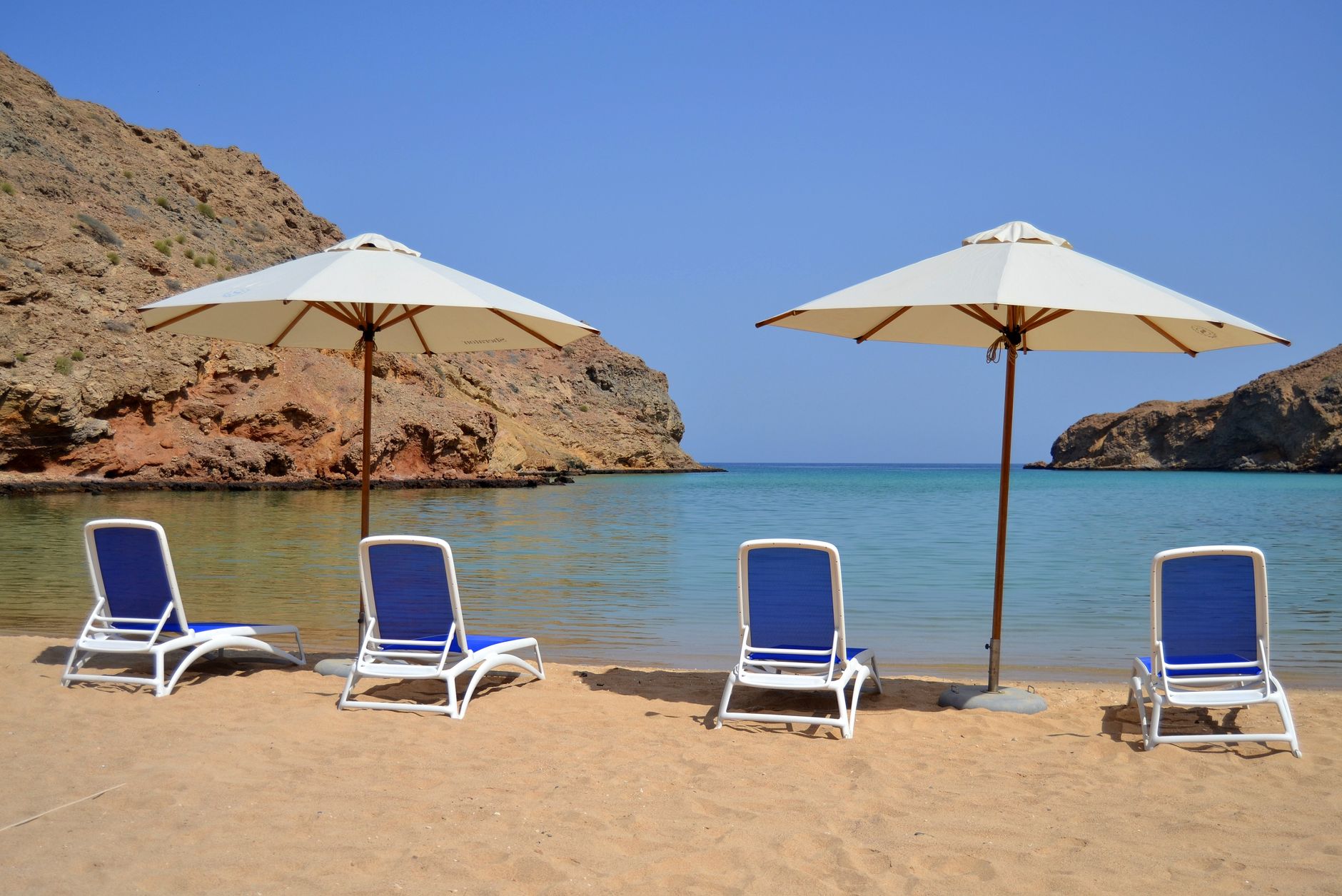 Peaceful sandy beach with umbrellas and sun loungers in Muscat, Oman.