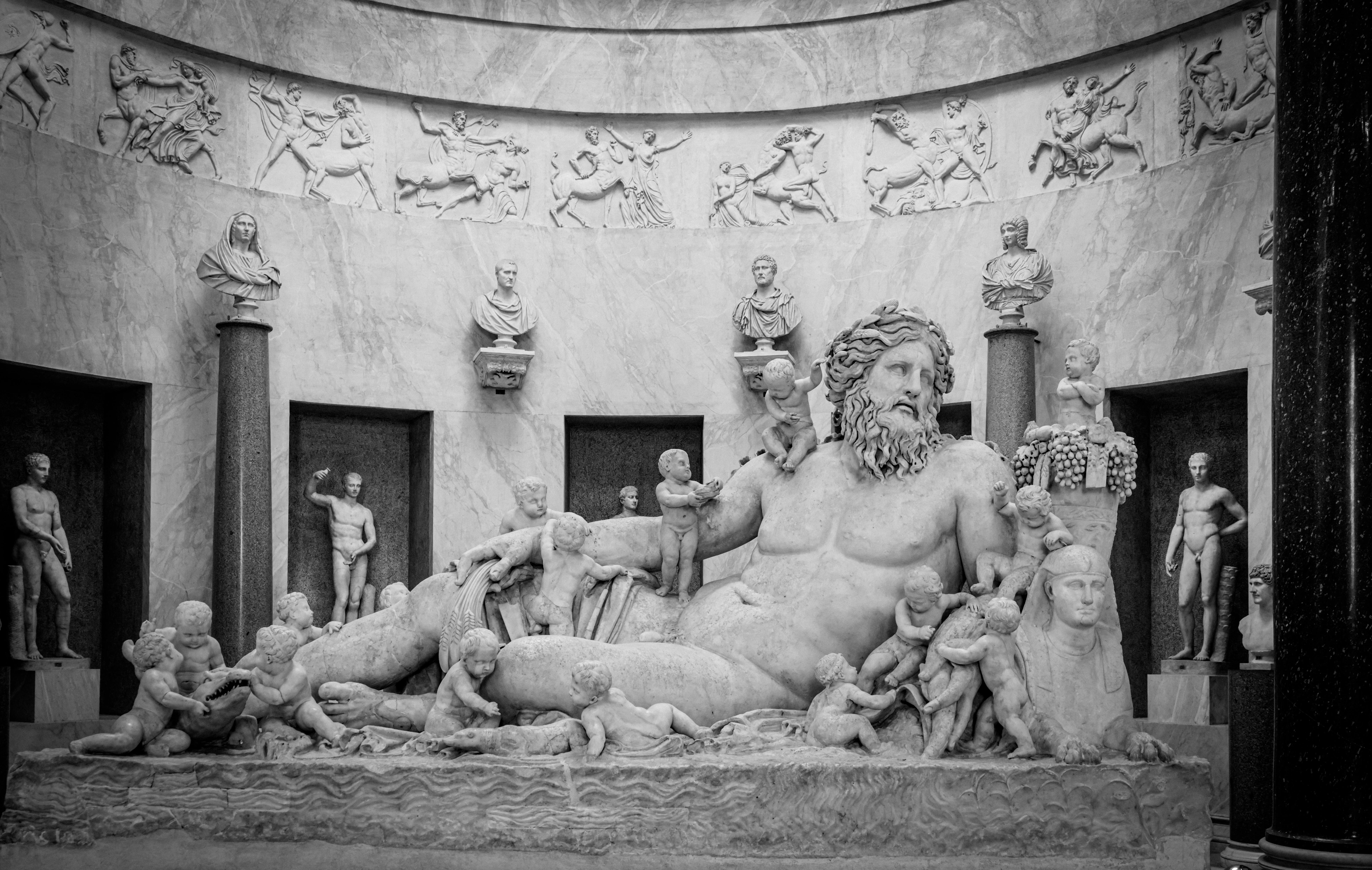 Intricate Roman marble statues depicting mythological scenes in an indoor display.