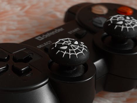 Close-up of a black gaming controller featuring a spider web design on the joysticks for entertainment enthusiasts.