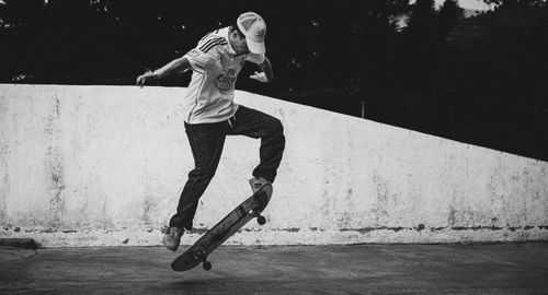 Free A young man performs a skateboard trick in an urban setting, captured in black and white. Stock Photo
