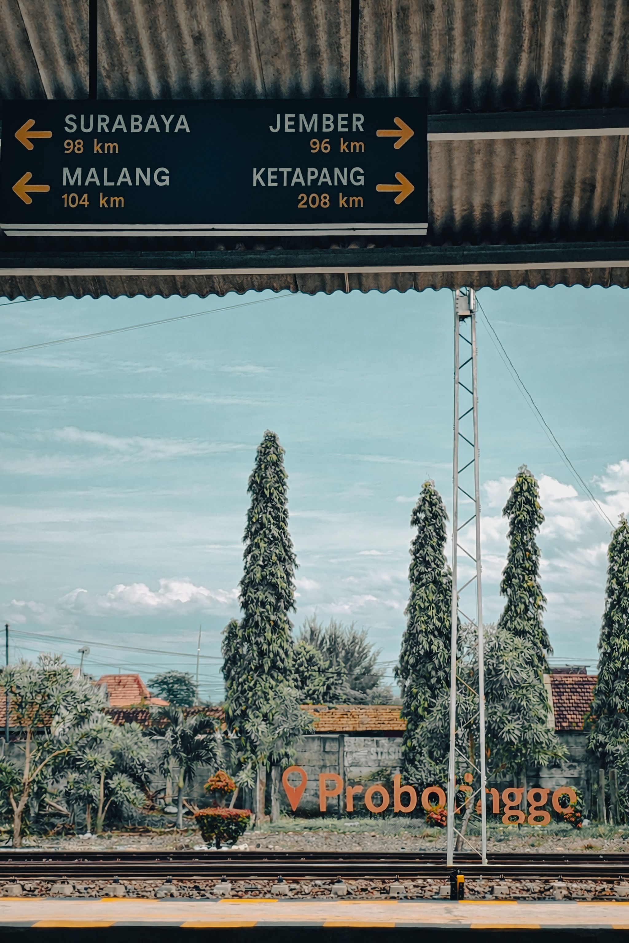 Probolinggo train station platform with direction sign showing distances to nearby cities.