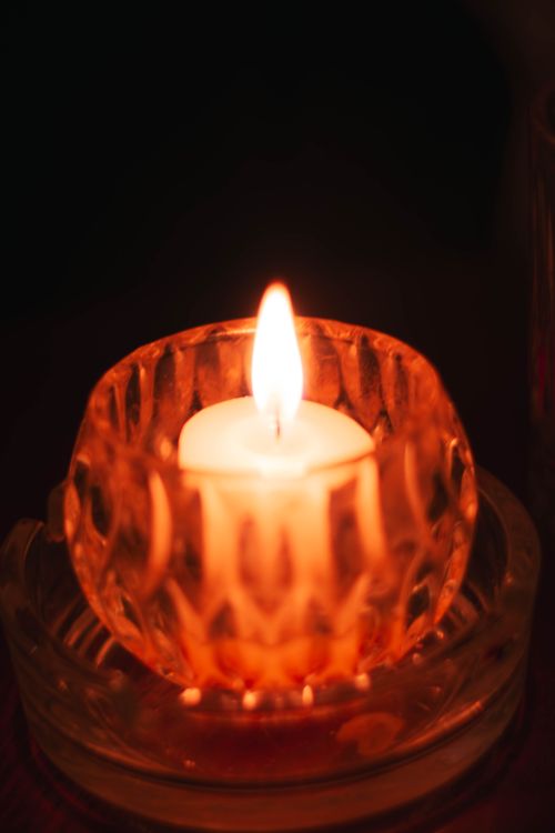 Free A close-up of a lit candle in a decorative crystal holder, casting a warm glow. Stock Photo