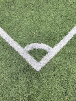 Detailed close-up of a white corner line on a green soccer field turf.