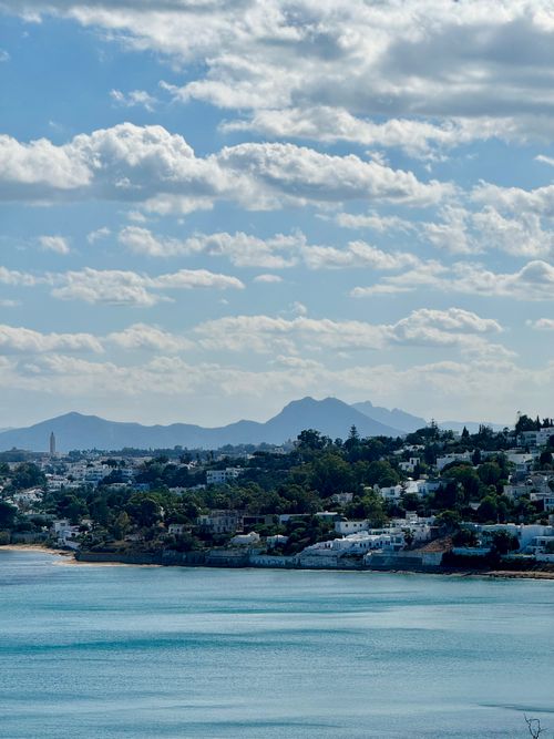 Free Panoramic view of a coastal city with mountains and a cloudy sky. Stock Photo