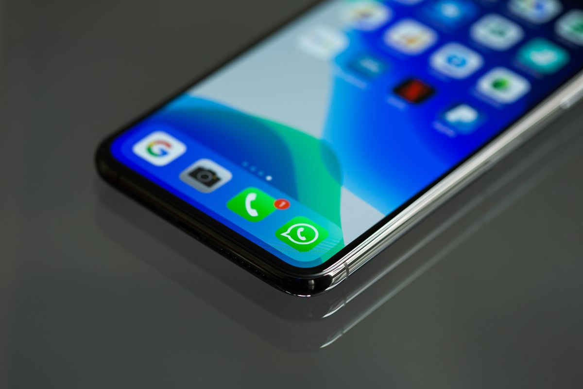 Ecran de telefon cu pictograme de aplicații, printre care WhatsApp, în prim-plan