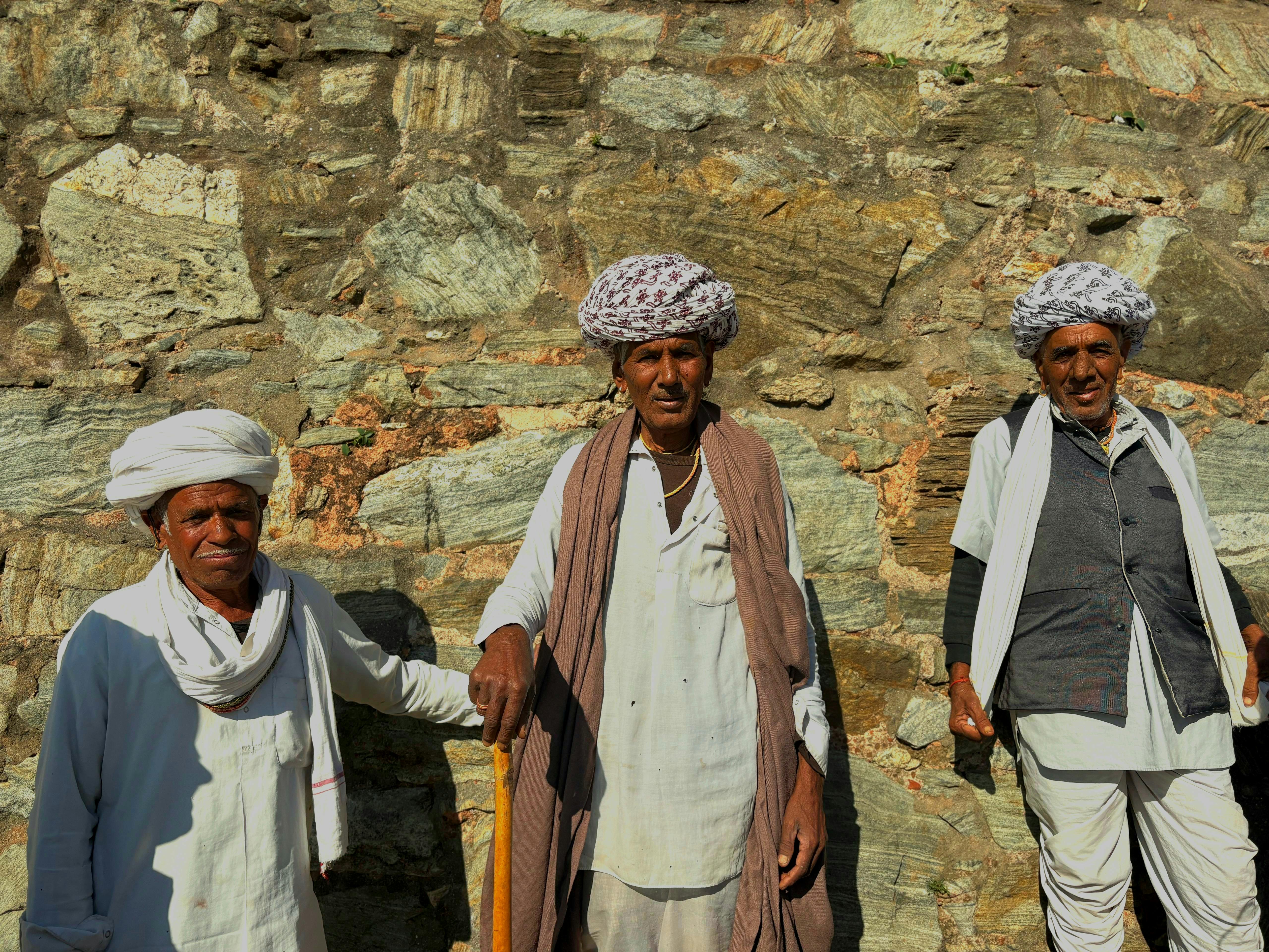 Gratis Tre uomini indiani tradizionali a RJ, in India, sono in piedi contro un muro di pietra. Foto a disposizione