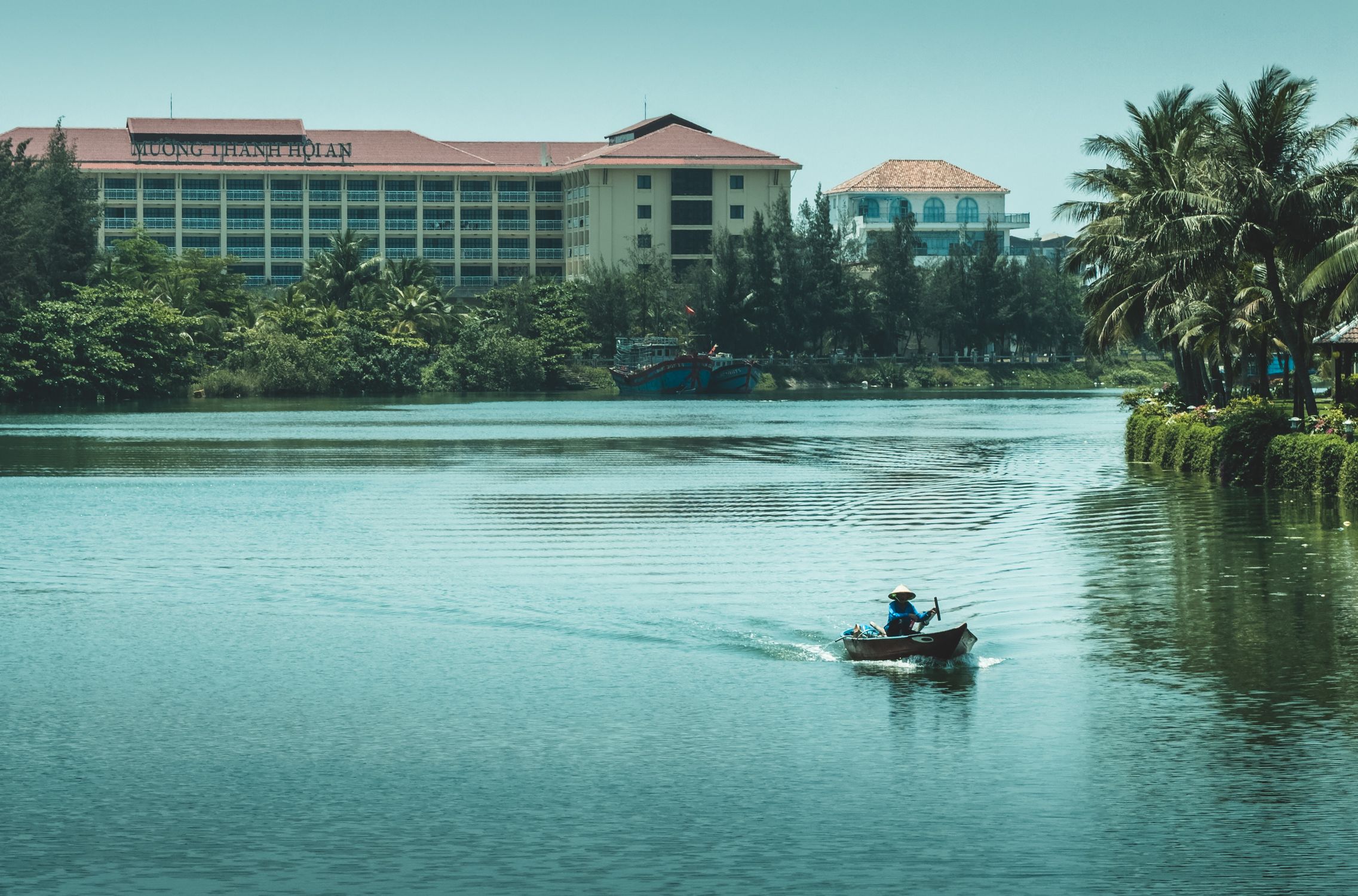 Peaceful river scene in Vietnam with a small boat in midstream, reflecting a tranquil lifestyle.