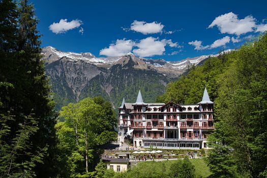Scenic view of a grand hotel nestled in the Alps with breathtaking mountain backdrop.