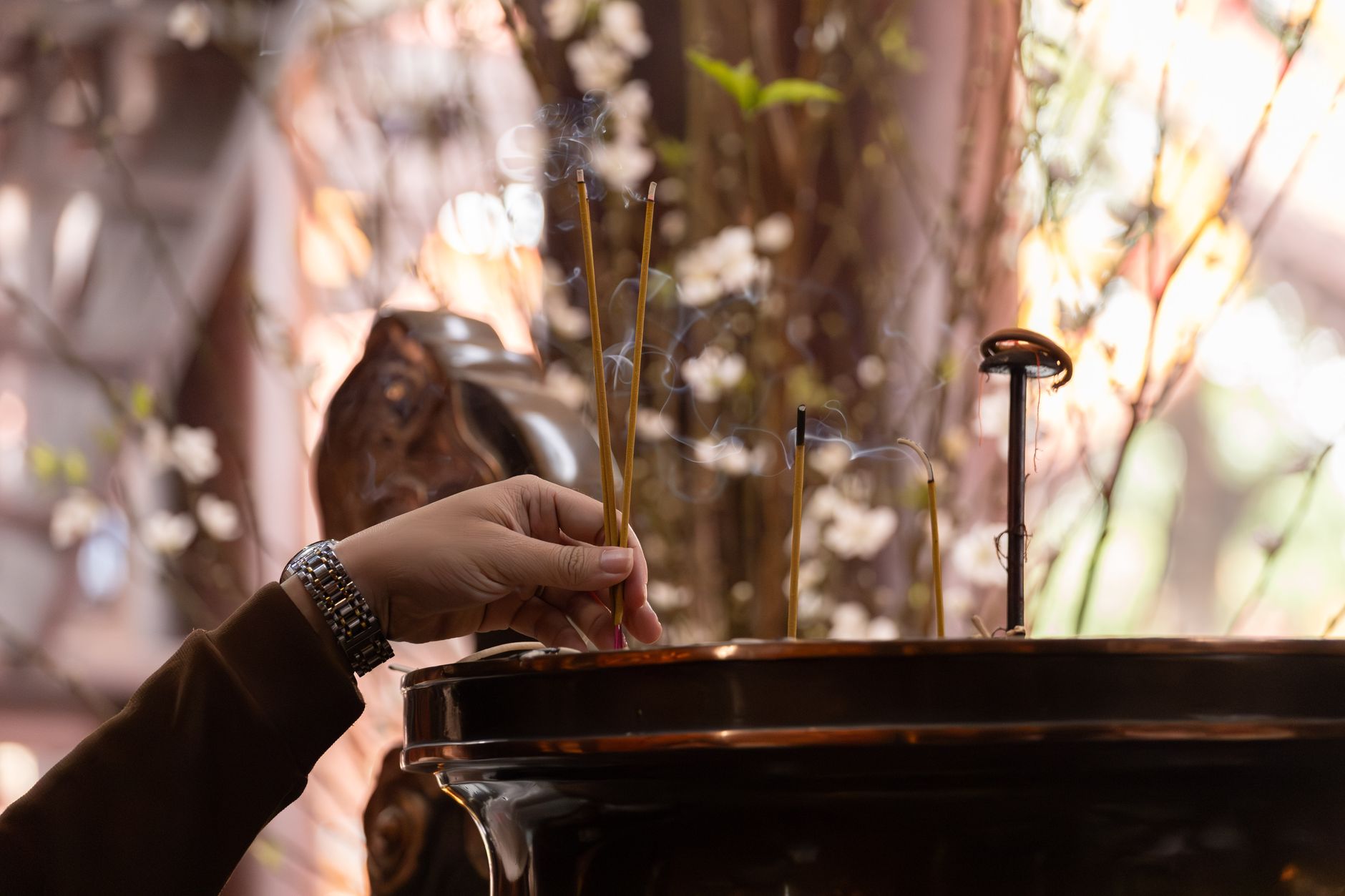 Close-up of a hand lighting incense sticks indoors, creating a spiritual atmosphere in Hanoi, Vietnam.