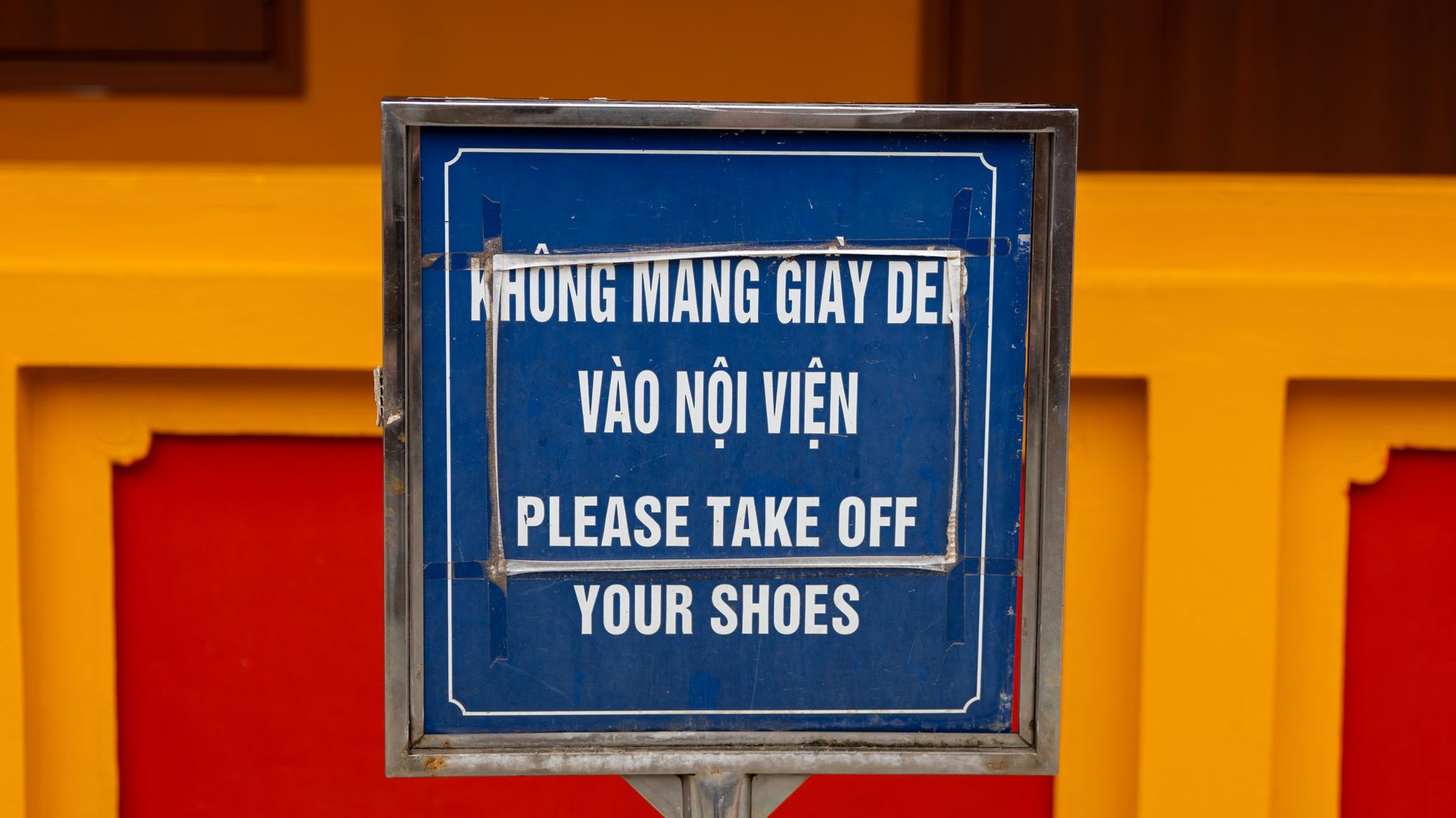 Close-up of bilingual sign in HΓ Nα»i, Viα»t Nam, advising to remove shoes before entering.