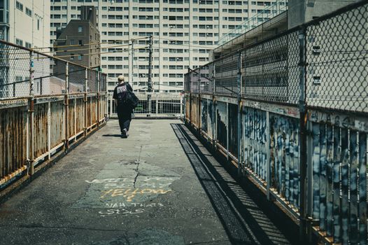 A person walks on a graffiti-covered urban walkway in Tokyo, Japan.