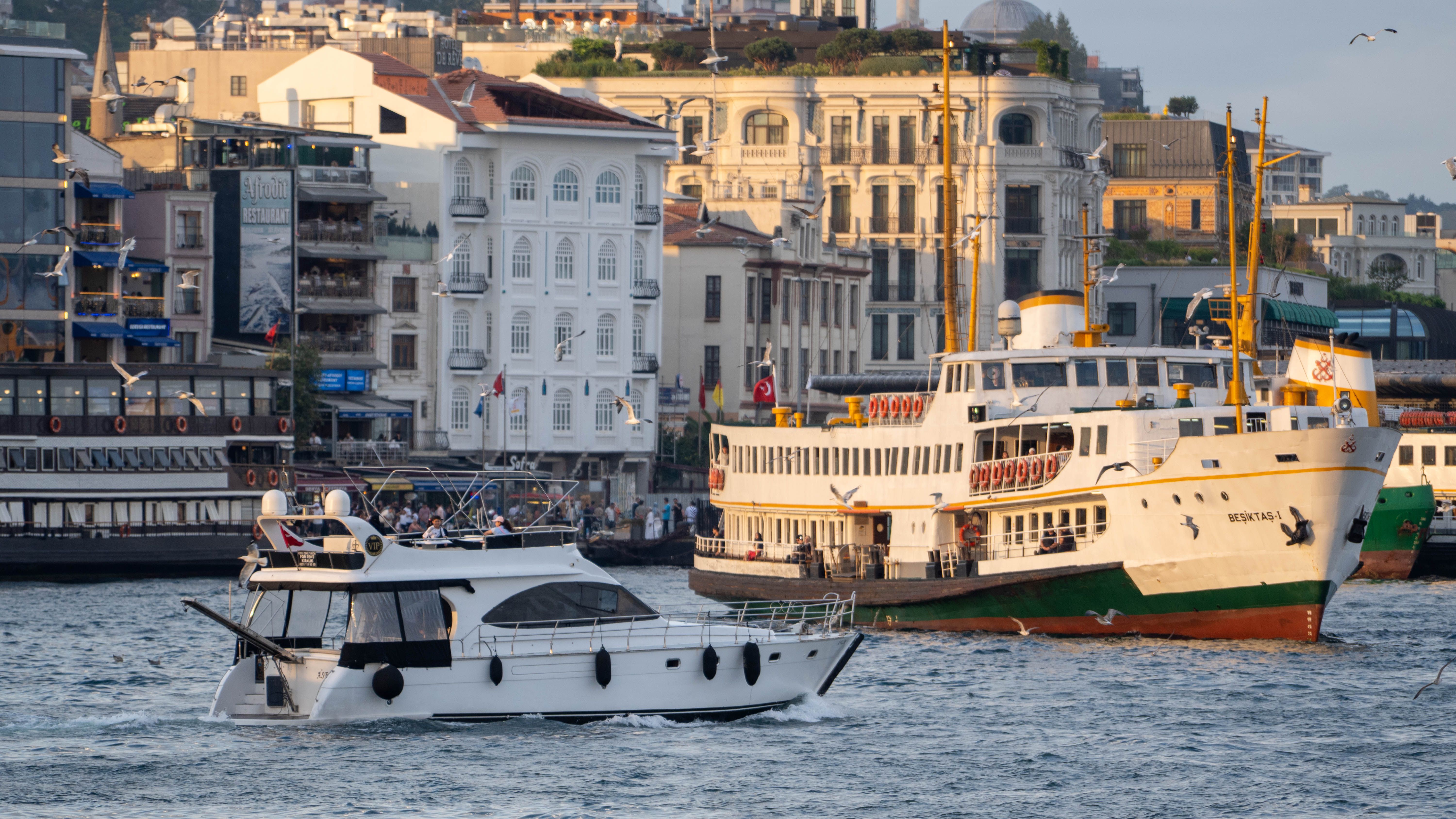 Elegant boats navigate the bustling Bosphorus with historic buildings in the background.