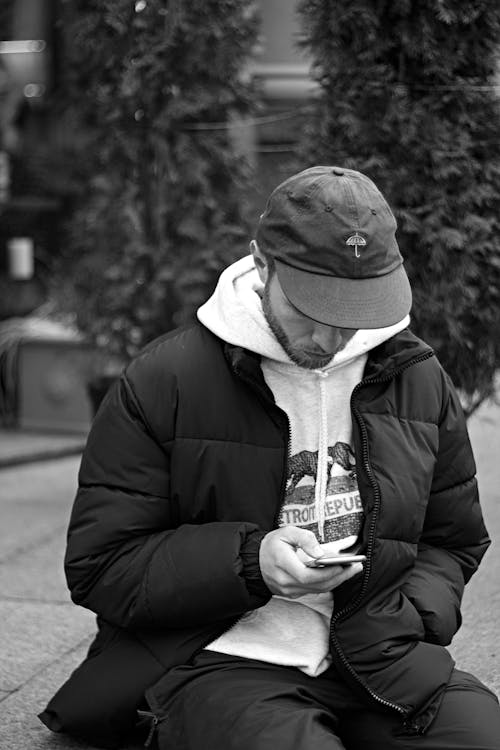 Monochrome Photo of Man Using His Cellphone