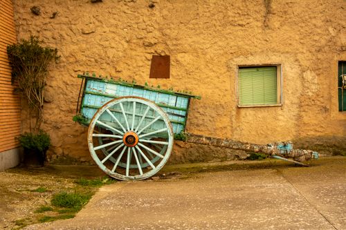 Free Old wooden cart leaning against a textured stone wall, creating a vintage, nostalgic feel. Stock Photo