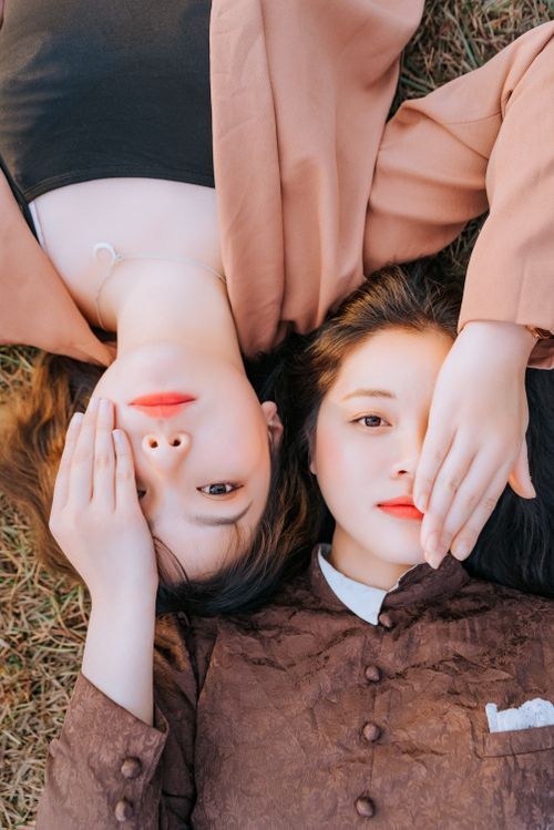 Free Glamorous outdoor portrait of two women laying on grass, showcasing fashion and beauty. Stock Photo