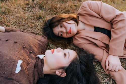 Free Two women lying on grass in a relaxed outdoor setting, conveying a calm and serene vibe. Stock Photo