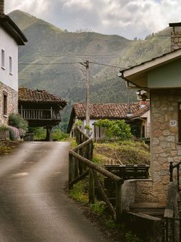Charming rural street in Cangas de Onís, Spain, with traditional stone houses and mountain backdrop.