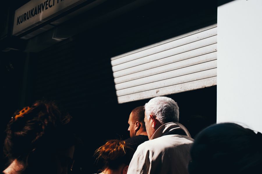 A group of people stand in line outside Kurukahveci Mehmet Efendi under dramatic lighting.