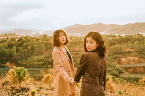 Free Two women in stylish outfits holding hands in a serene outdoor landscape. Stock Photo