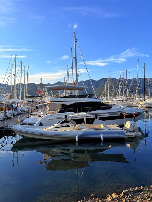 Free Peaceful marina scene with luxury yachts reflecting in calm water under a clear blue sky. Stock Photo
