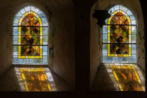 Free Beautiful stained glass windows in a church casting colorful light patterns indoors. Stock Photo