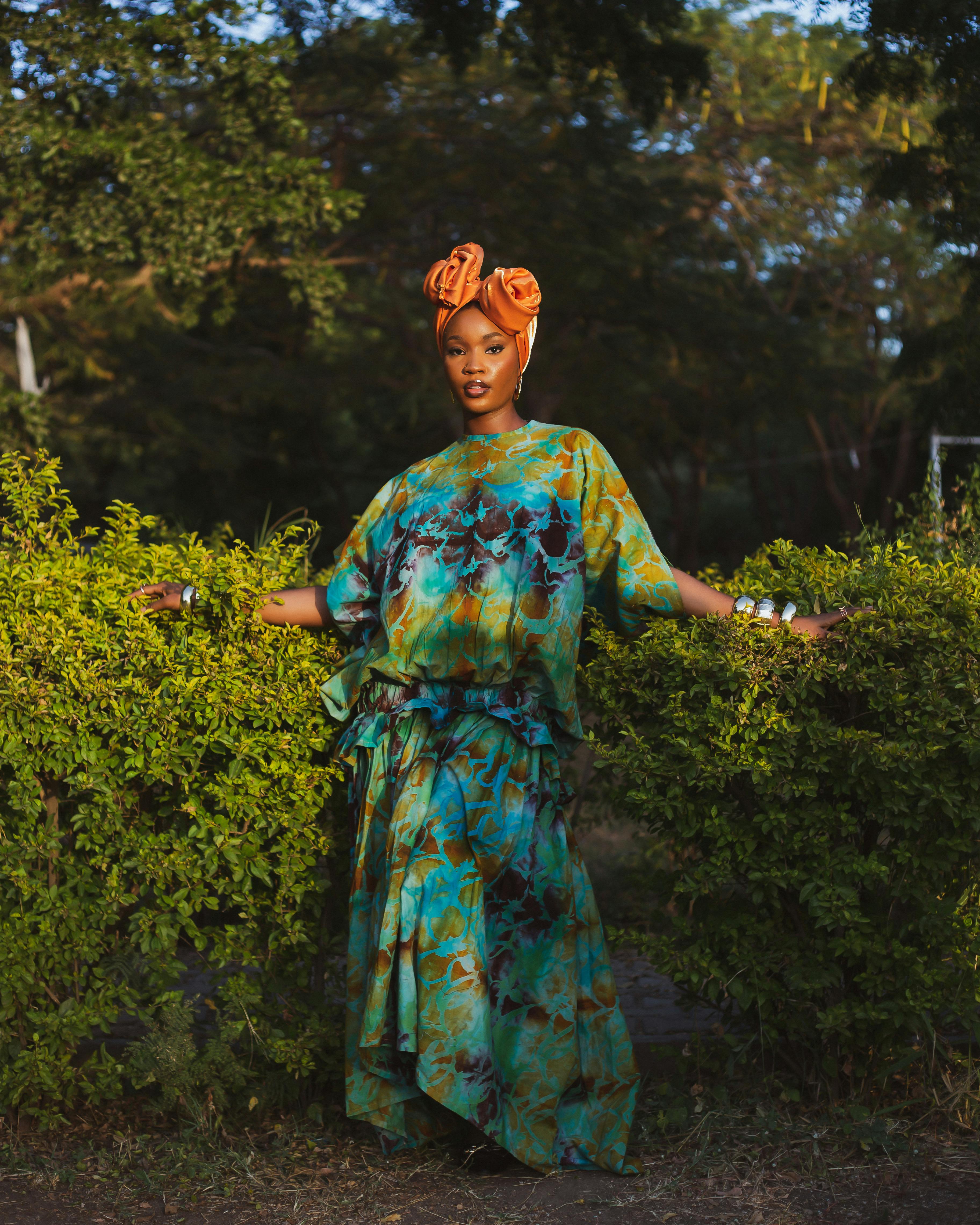 Δωρεάν Γυναίκα στέκεται με αυτοπεποίθηση σε εξωτερικό χώρο με έντονο αφρικανικό φόρεμα και κάλυμμα κεφαλής. Φωτογραφία από στοκ φωτογραφιών