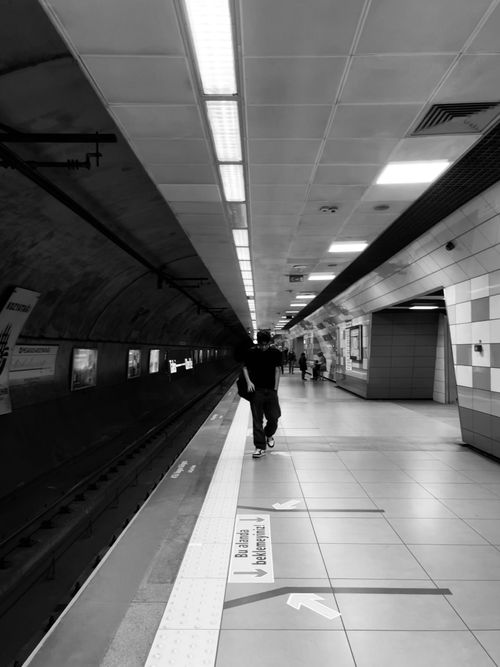 Free Black and white subway station scene with people walking along the platform. Stock Photo
