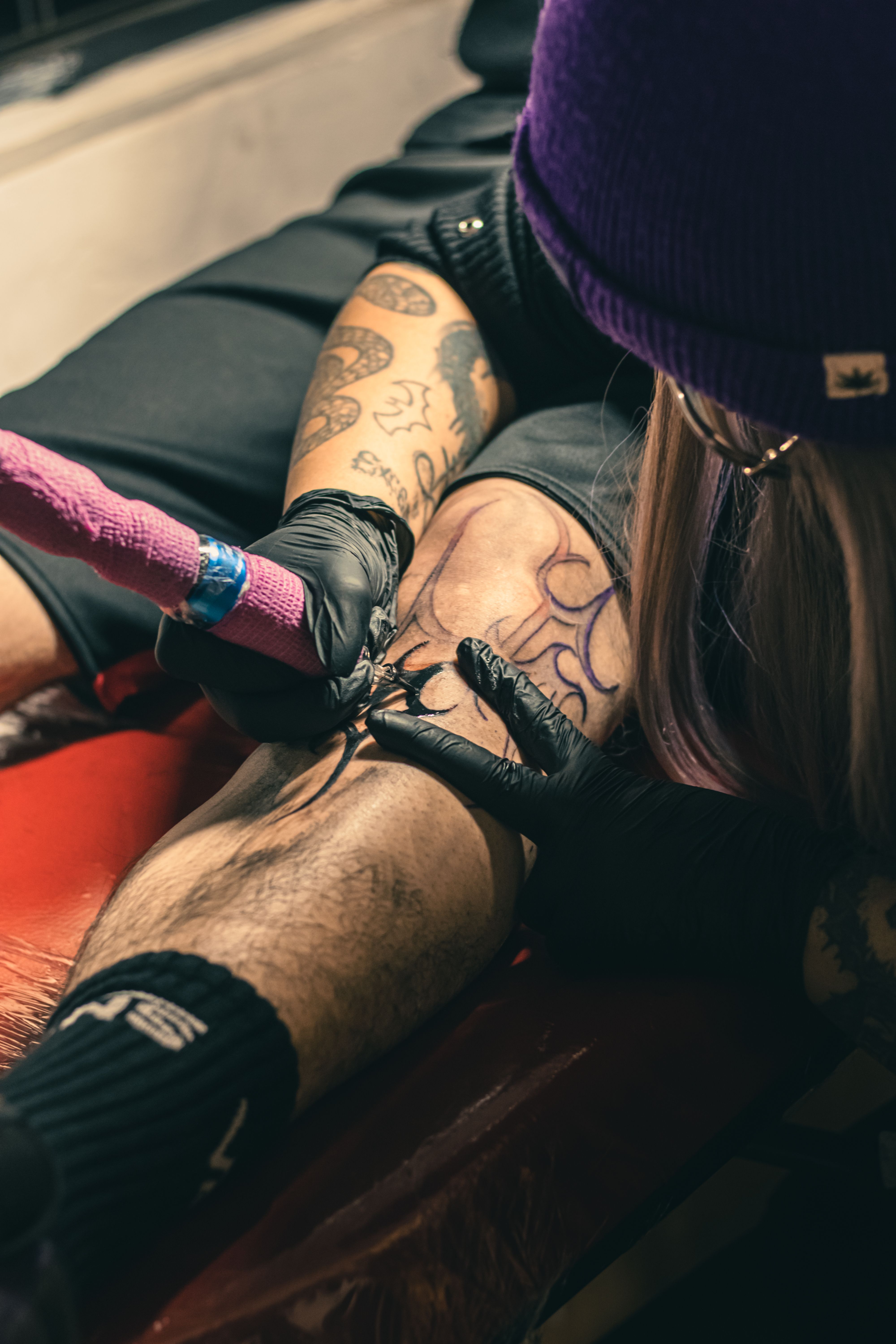 Detailed view of a tattoo artist working on a client's leg in a studio, Ciudad de México.