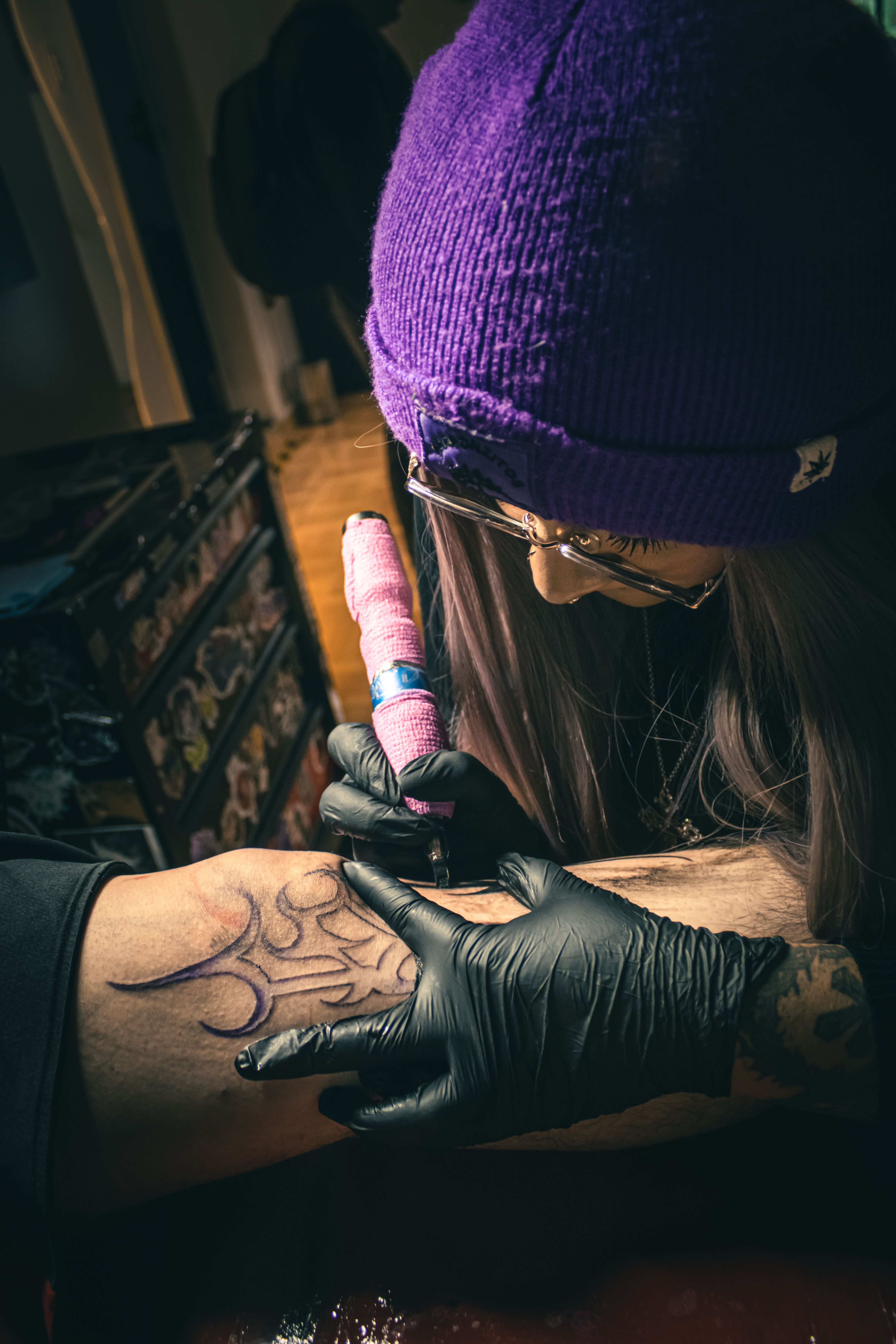 A tattoo artist crafting detailed ink art on a client's arm in a tattoo studio setting.