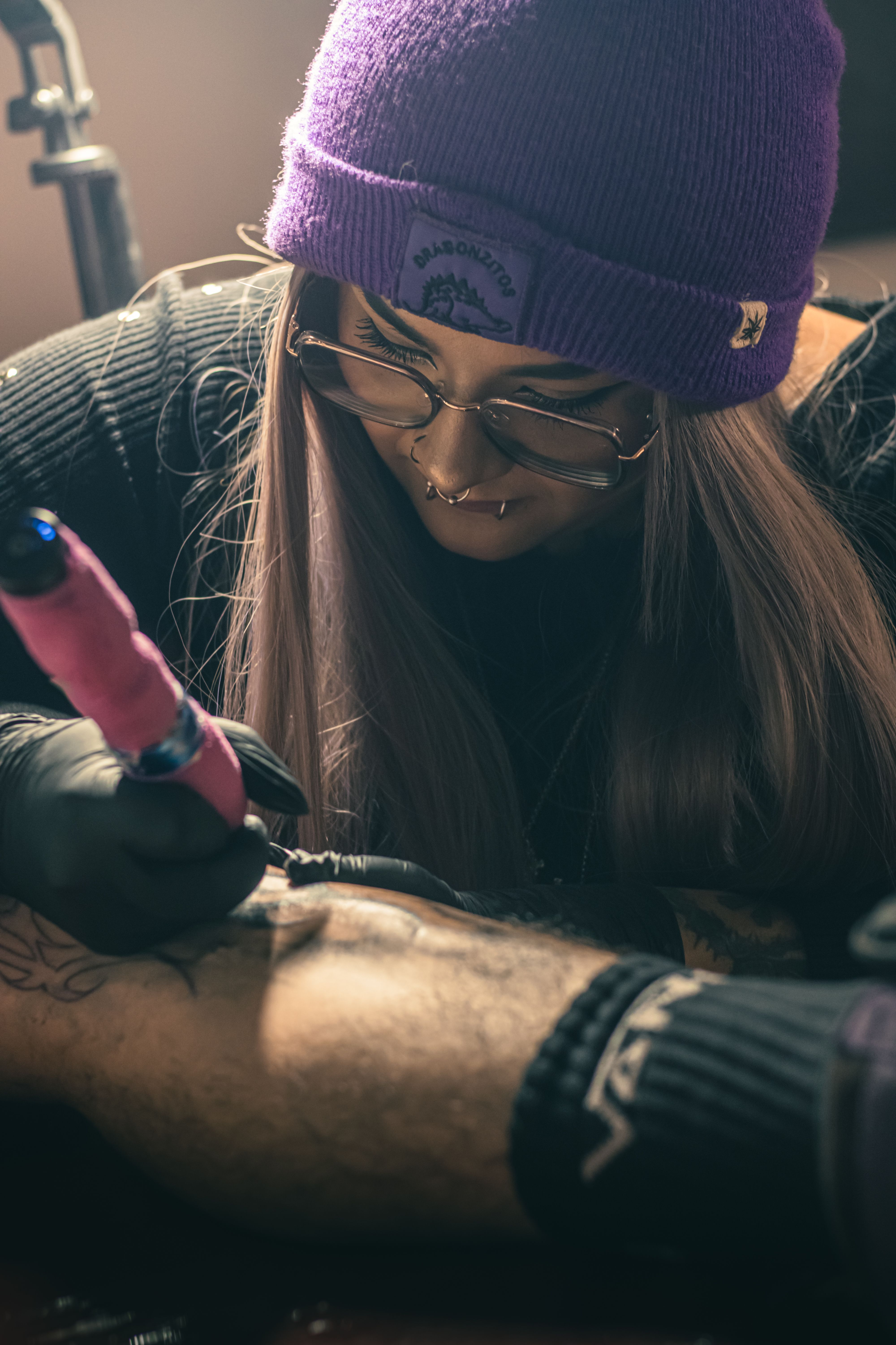 A tattoo artist focused on designing a leg tattoo in a Mexico City studio. Captured with vibrant lighting.