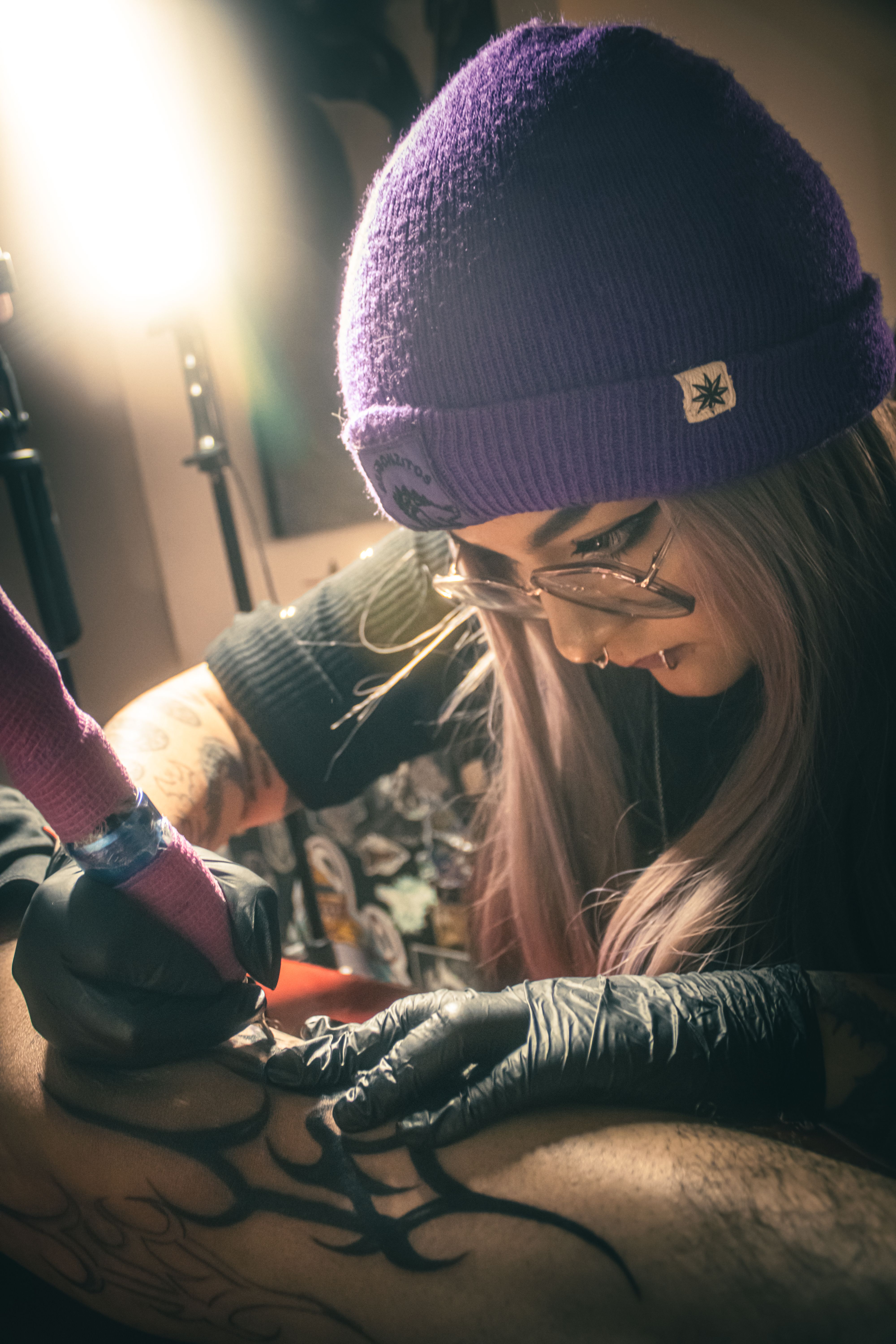 Close-up of a tattoo artist working on a tribal leg design in a tattoo studio, creating intricate patterns.