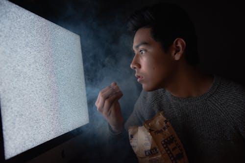 Free Man Eating Chips While Watching Tv Stock Photo