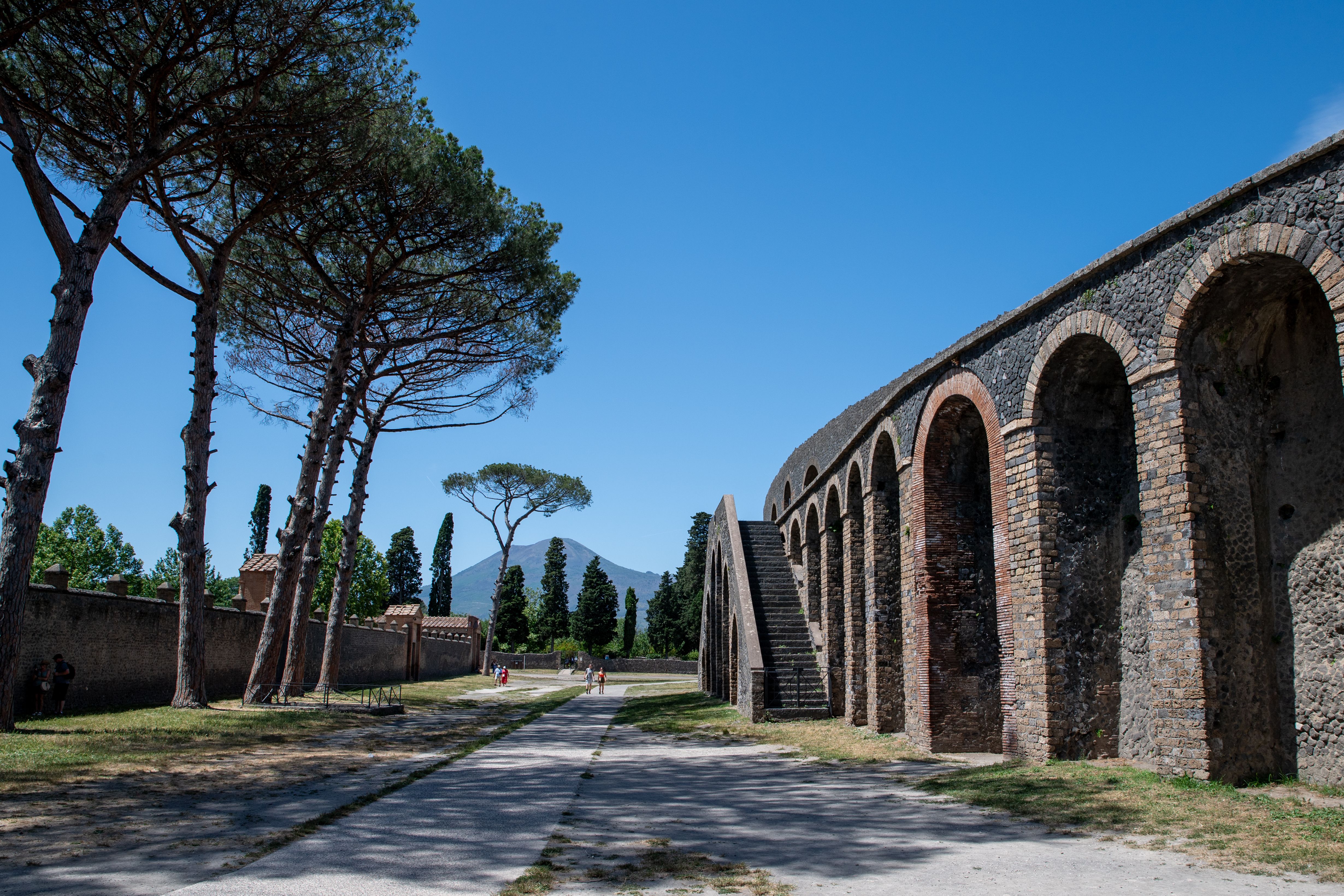 Ruínas antigas de Pompeia, em Itália, com o Monte Vesúvio visível ao longe, sob um céu azul limpo