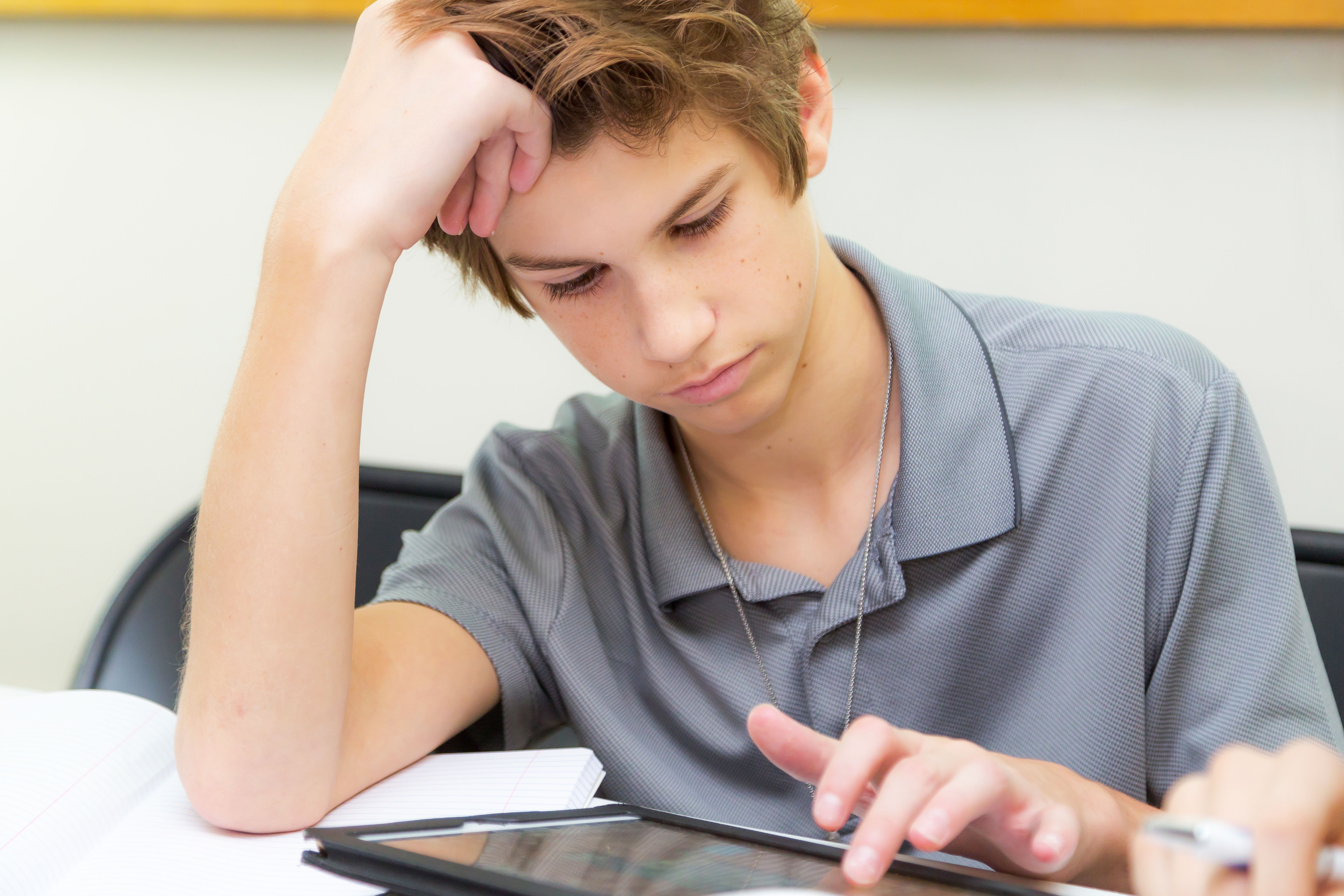 student excitedly looking at a progress bar on a tablet in a classroom