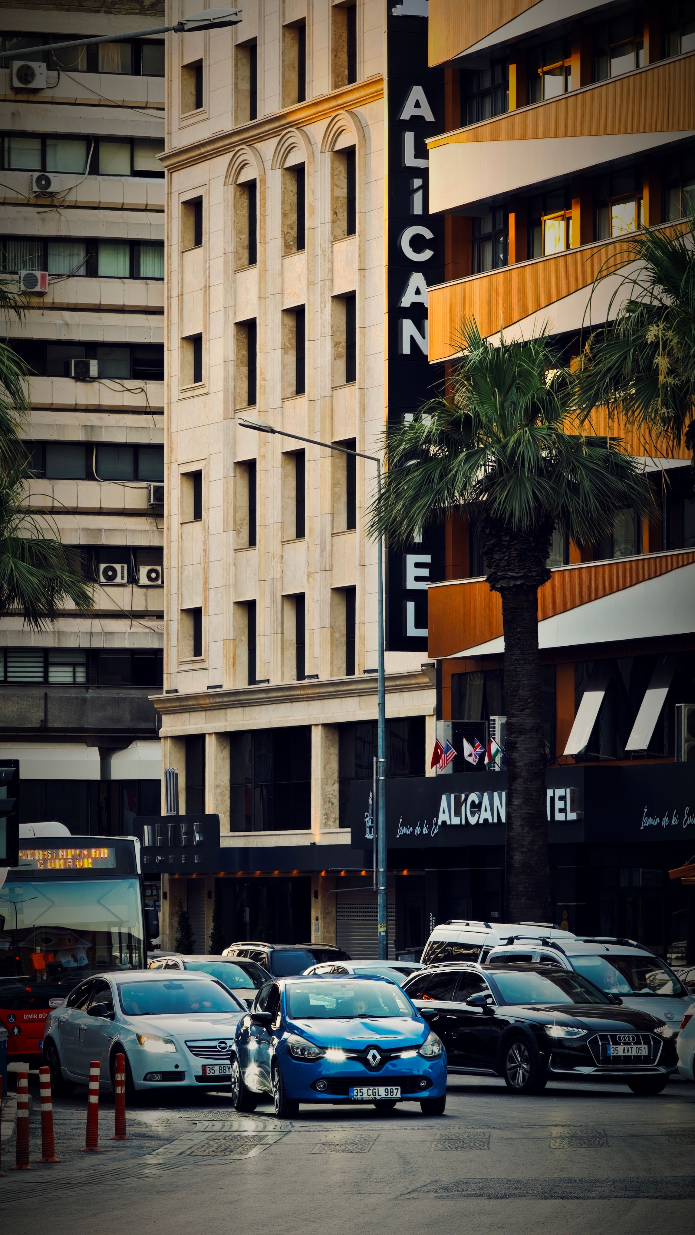 Urban scene featuring a hotel with palm trees and traffic in a bustling city area.