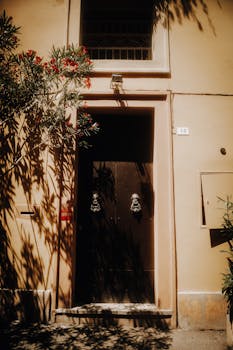 Sun-dappled entrance with ornate accents on an urban street, adding rustic charm.