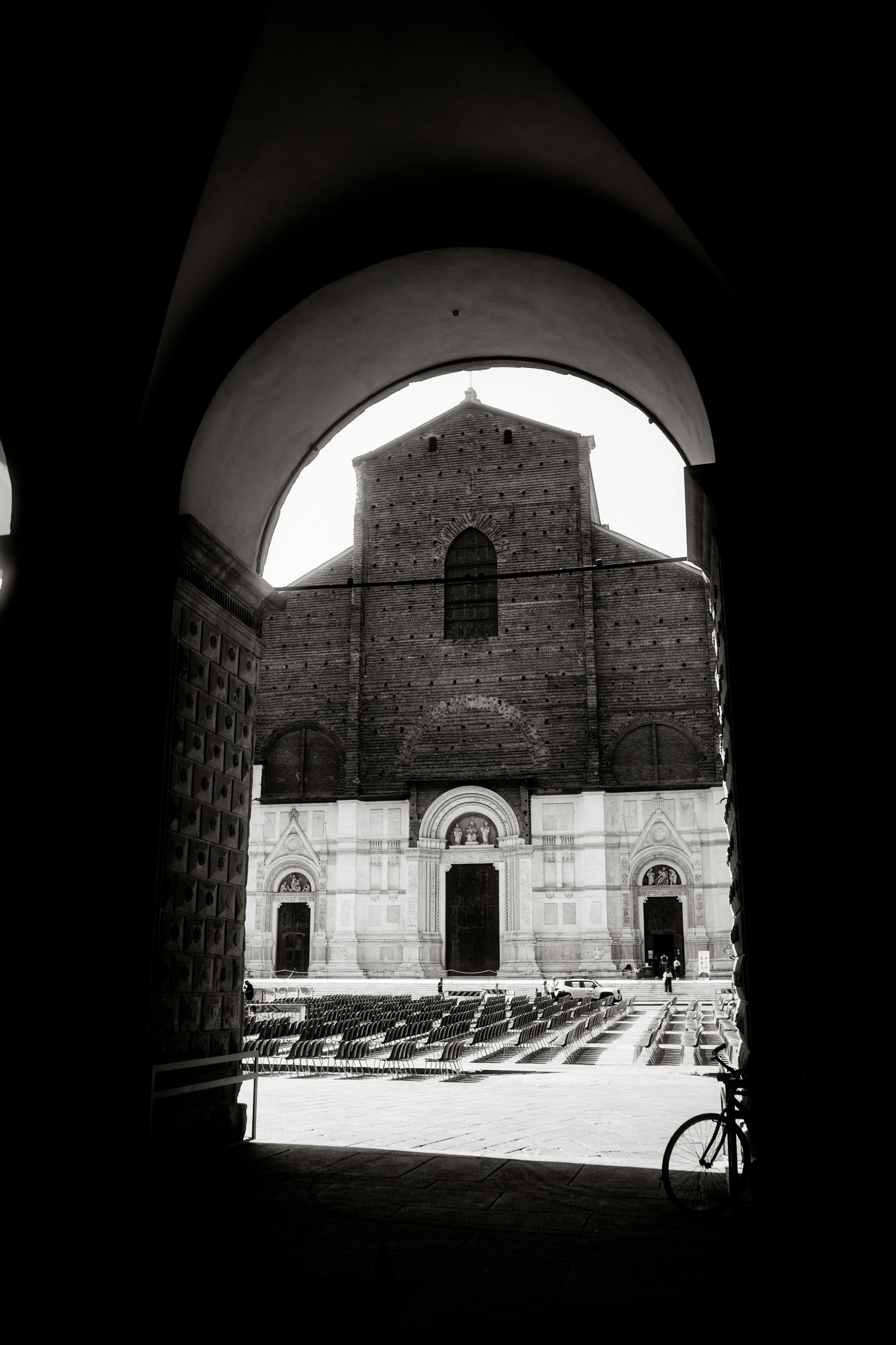 Dramatic black and white photo of a historic church through an archway.