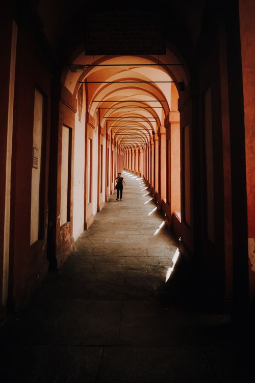 Free Long corridor with arches and a silhouette of a person walking, creating dramatic effects. Stock Photo