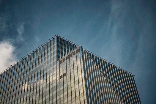 A striking view of a modern glass skyscraper in Bangkok set against a dramatic sky.