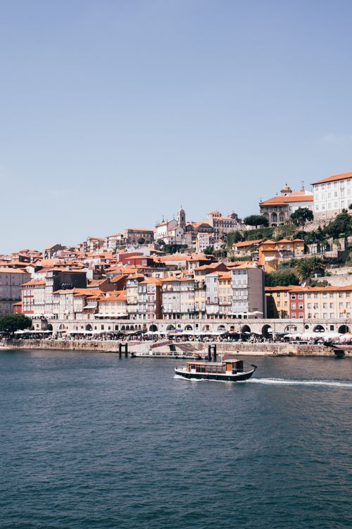 Free Charming view of Porto's Ribeira district and Douro River with a scenic boat under a clear sky. Stock Photo