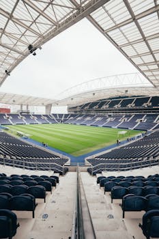 Wide-angle view of a contemporary stadium featuring empty bleachers and a well-maintained grass field, perfect for various sports.