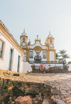 从古老的石头教堂上方向下望去，鹅卵石街道旁装饰着墙壁，晴天时还有马车经过