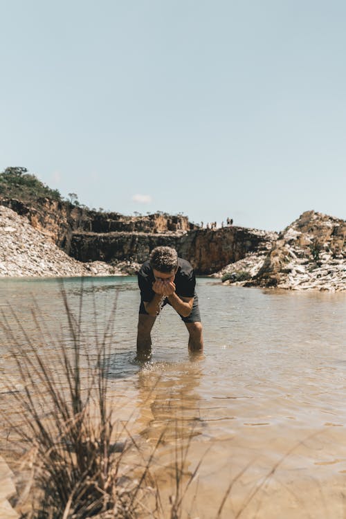 Man washing face in lake on sunny day