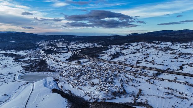 Stunning aerial shot of a snow-laden mountain valley under a clear blue sky.