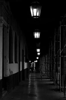 Atmospheric black and white photo of a dimly lit urban alleyway at night.