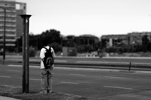 Free A lone figure with a backpack stands on an urban street, creating a moody city scene. Stock Photo